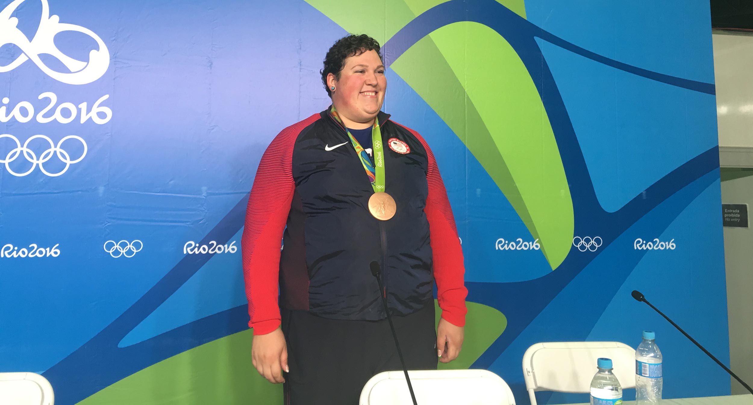 A U.S. weightlifter smiles with her bronze medal
