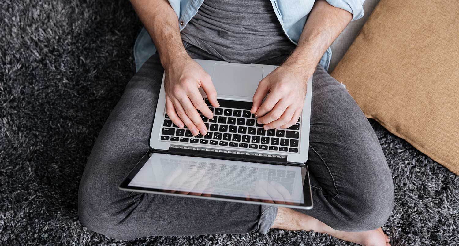 Person sitting on floor typing on a laptop