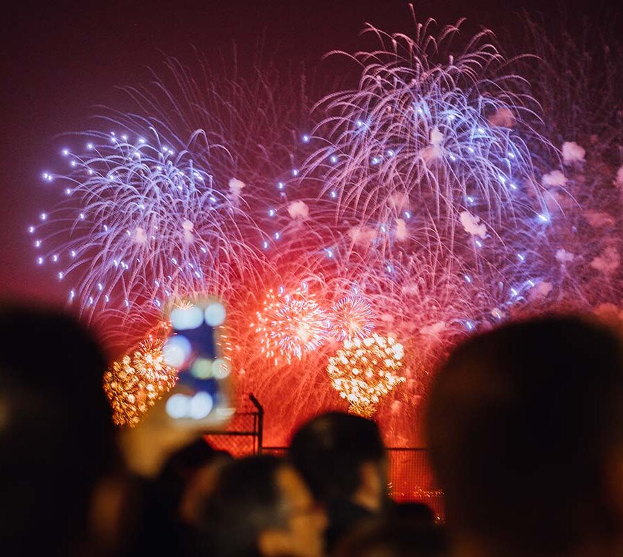 A mix of red and blue fireworks as a crowd watches on