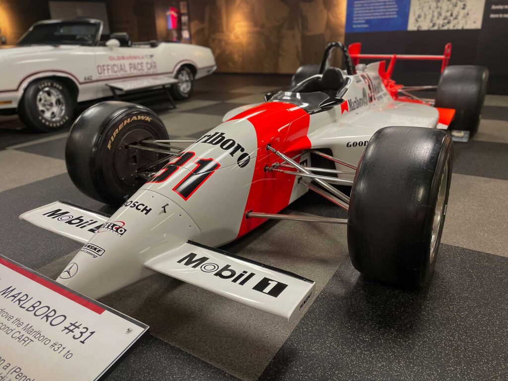 A orange and white open wheel race car in a museum