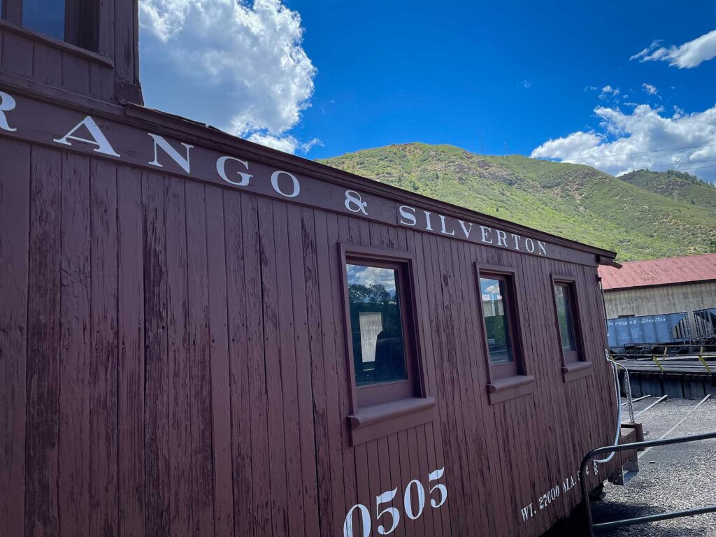 A red caboose with mountains in the background