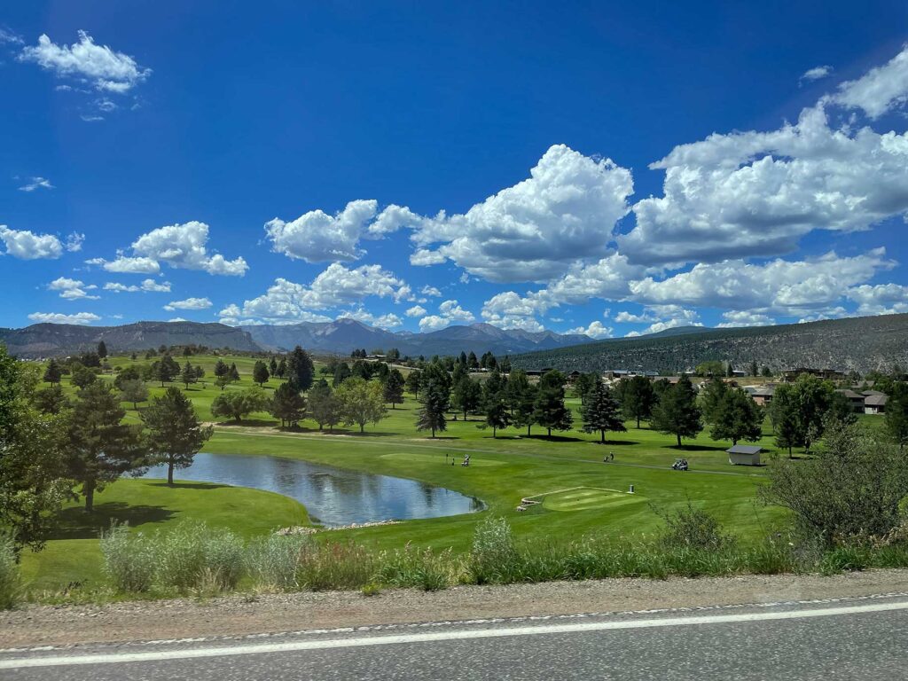 A green golf course with mountains in the distance