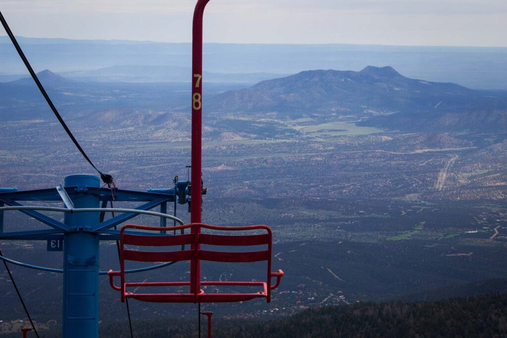 A stationary chairlift with the land below the mountain in the background