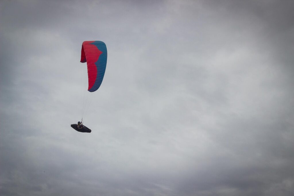 A paraglider flies beneath the clouds