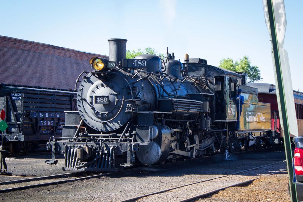 A steam engine sits in a rail yard