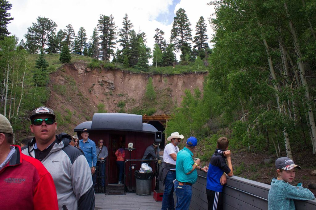 People in a gondola car on a train emerging from a tunnel
