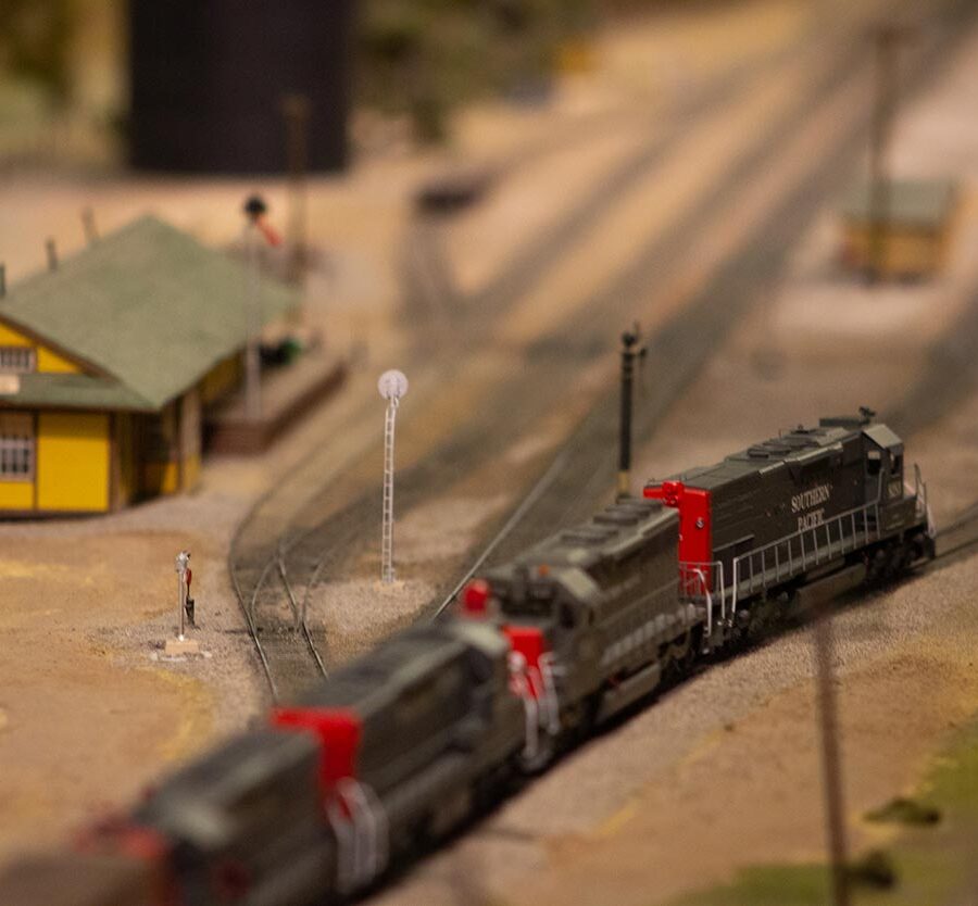 A Southern Pacific train running passed a yellow depot on a model train layout