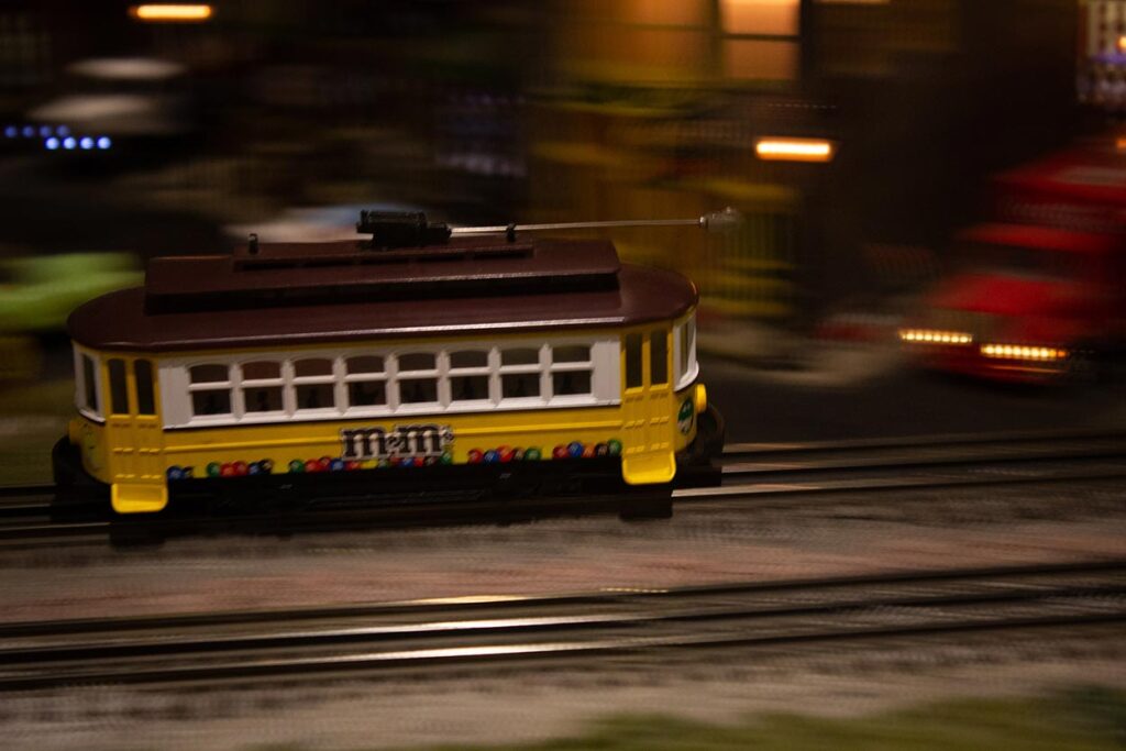 A yellow trolley running on a model train layout
