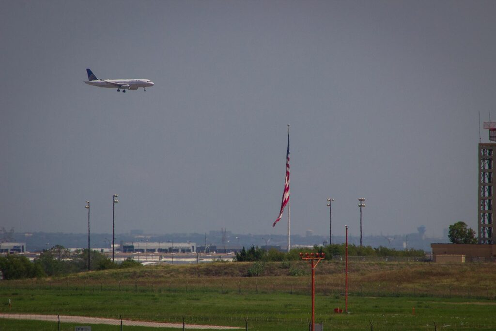 A United plane landing in the distance with the American flag in the foreground