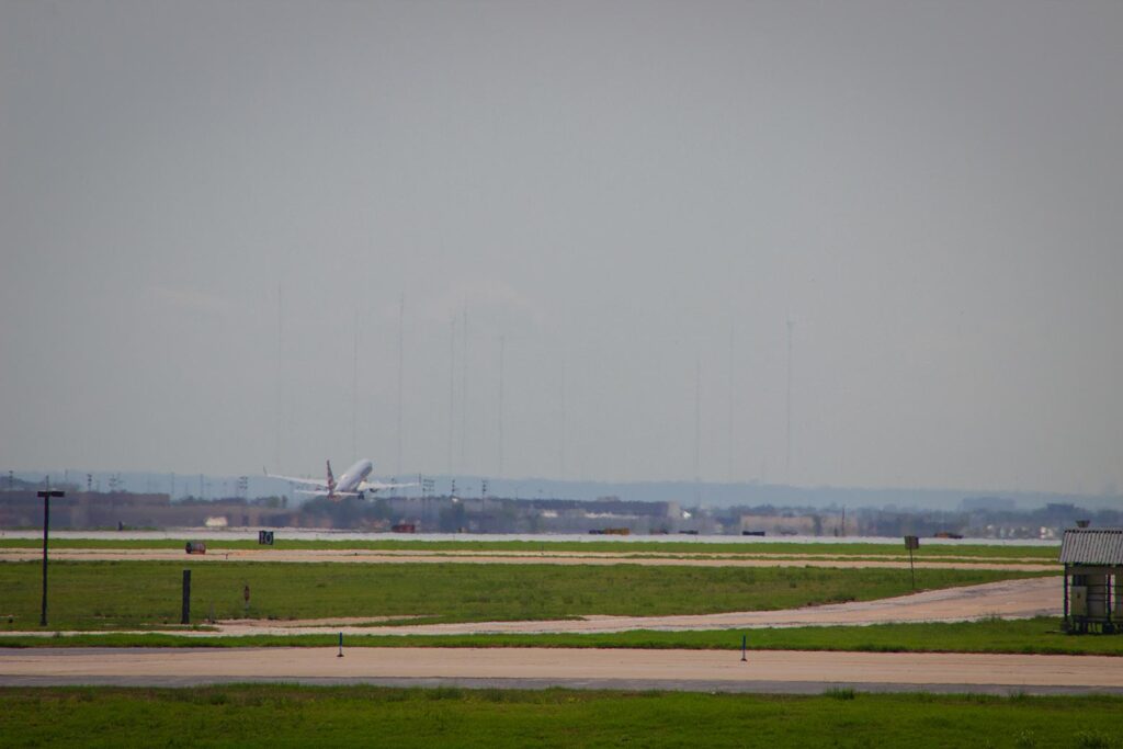An American Airlines plane taking off at a distance from an airport