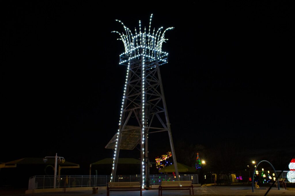 Colored lights in a park at night depicting an oil derrick