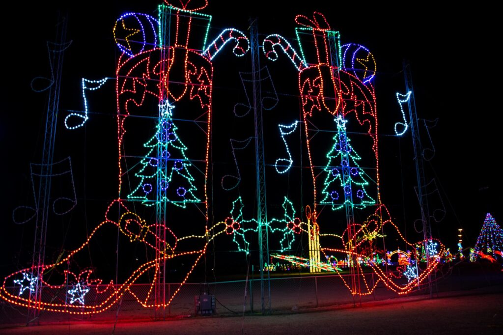 Colored lights in a park at night depicting two large cowboy boots with presents