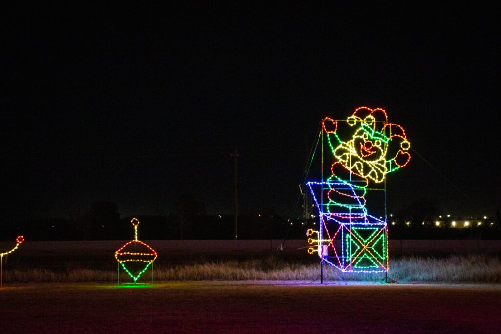 Colored lights in a park at night depicting a jack in the box toy