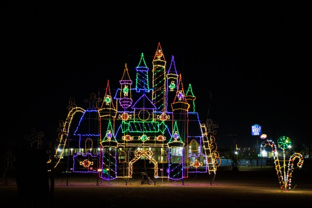 Colored lights in a park at night depicting a large castle