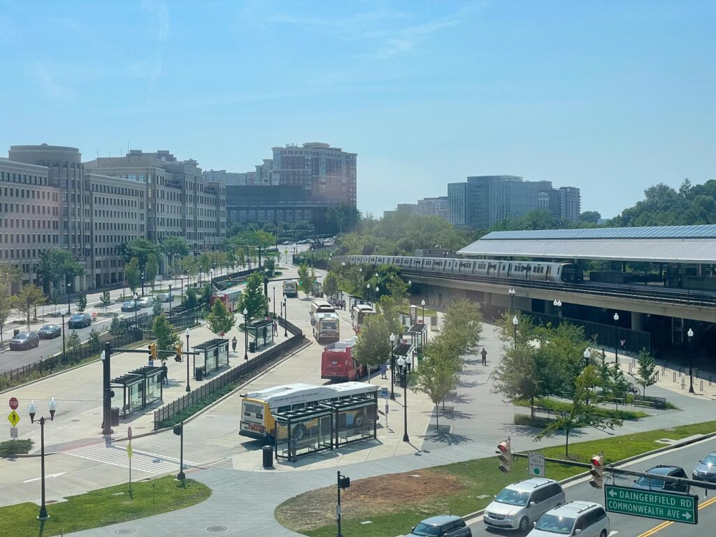 A metro station with a train arriving, a bus station and downtown buildings