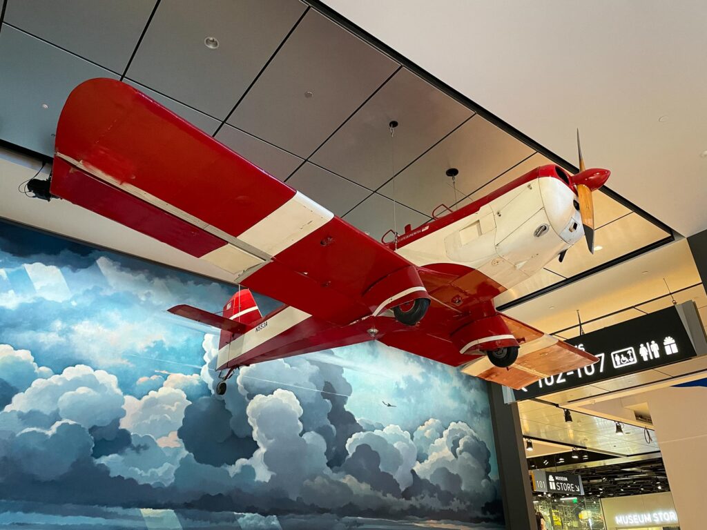 A red and white airplane hanging in a museum