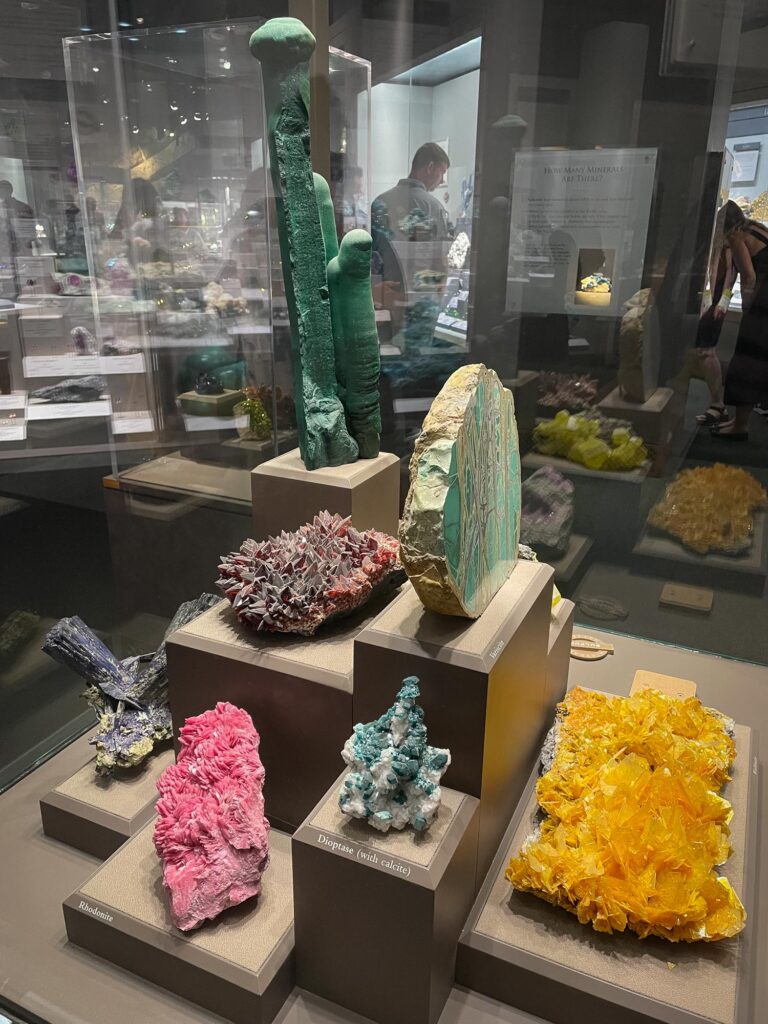 Various large, colorful gemstones in a glass case in a museum exhibit
