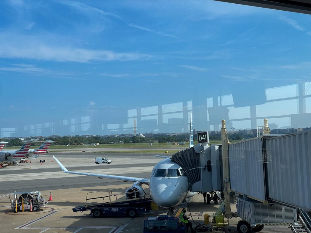 A airplane at an airport gate with the Washington Monument in the distance