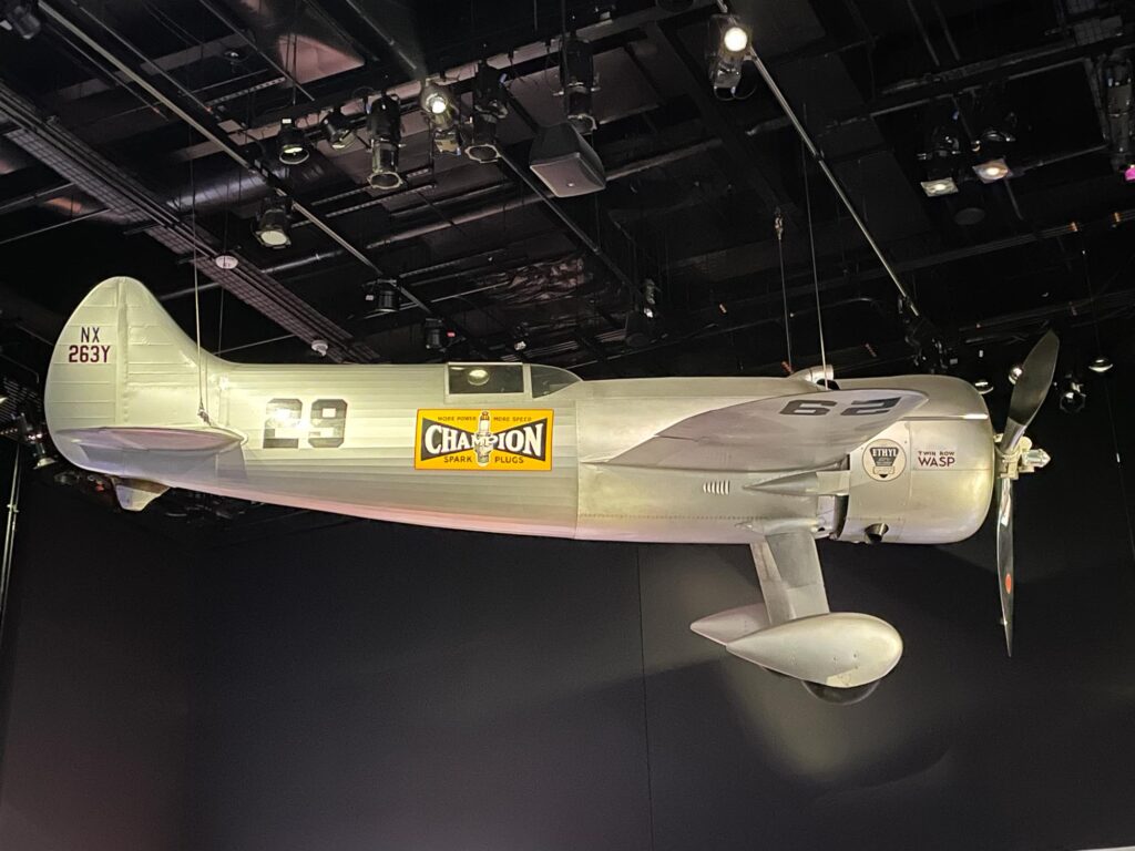 A silver airplane hanging in a museum