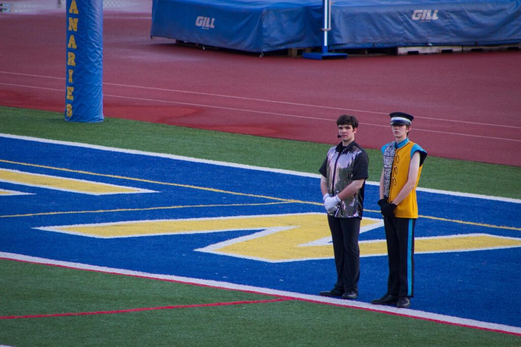 two members of a drum corps standing in the end zone
