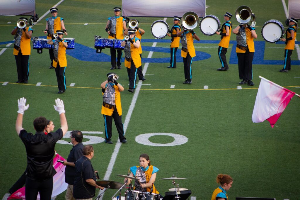 A drum corps performing in yellow, blue and silver uniforms