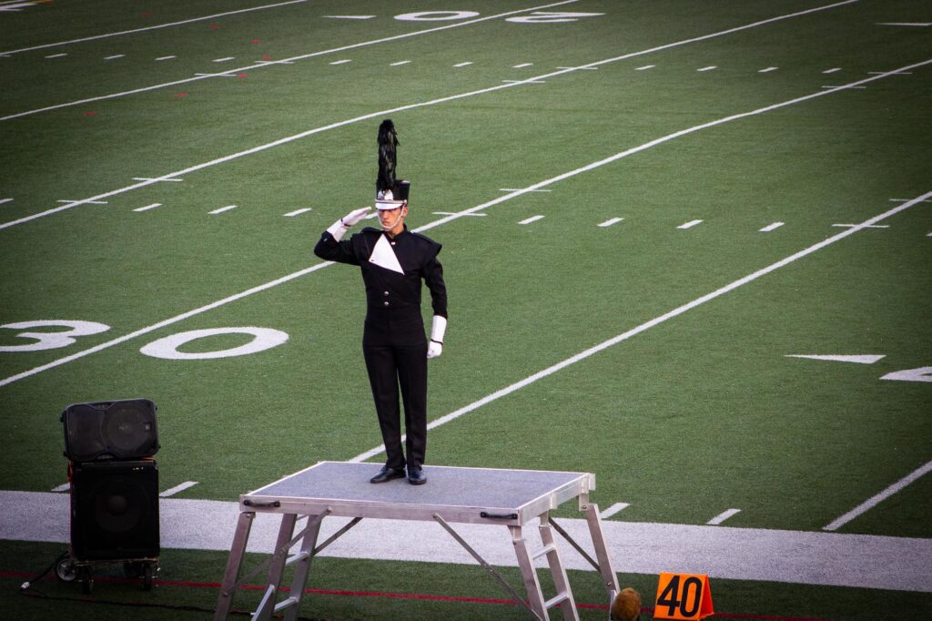 A drum corps drum major saluting the crowd