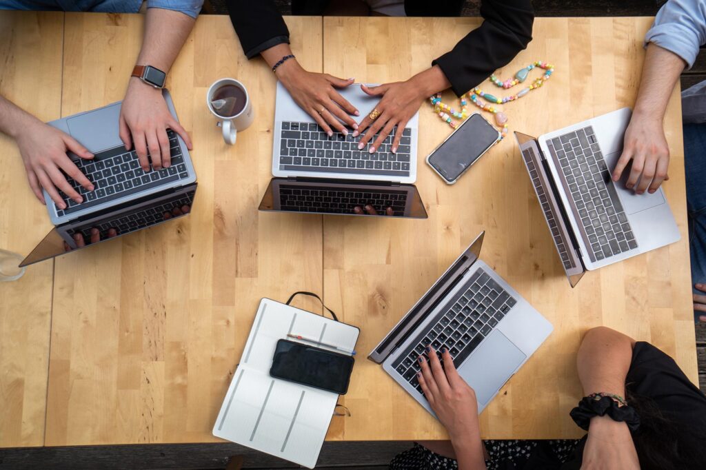 a group of people working on laptops on a wooden desk