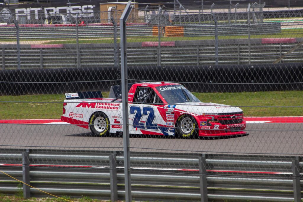 A red, white and blue race truck driving on a racetrack