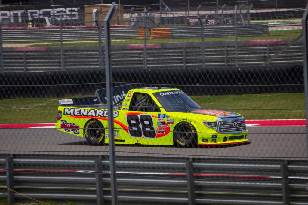 A yellow race truck driving on a racetrack