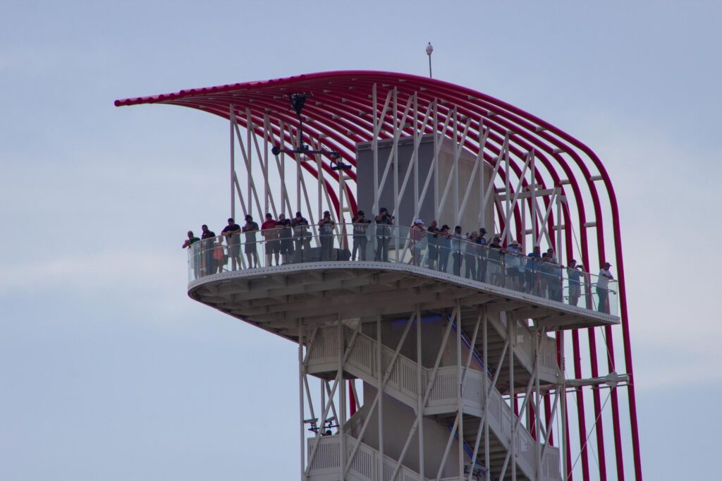 People watching a race from a tall red and white observation tower