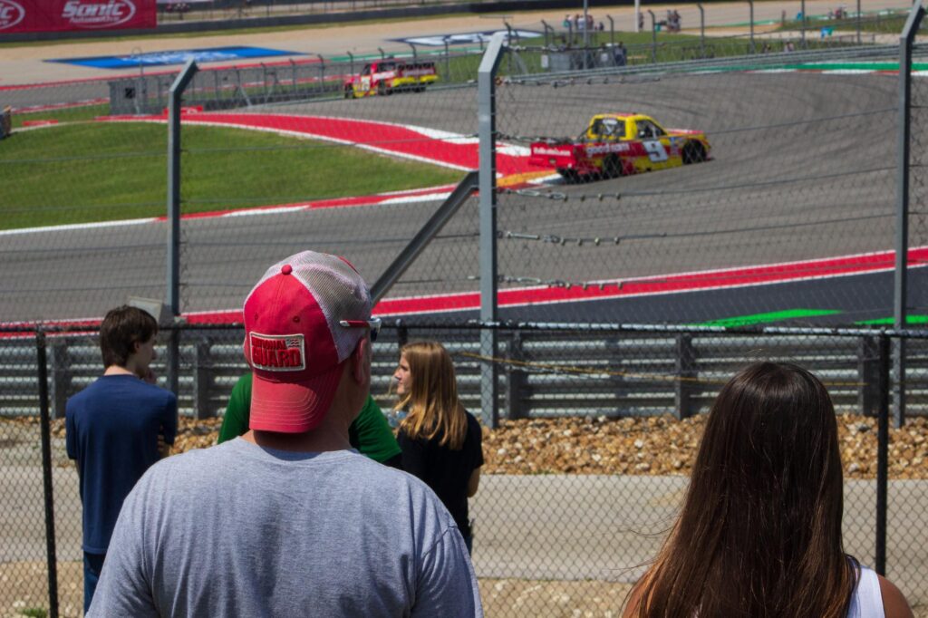 People watching two stock trucks racing on a racetrack