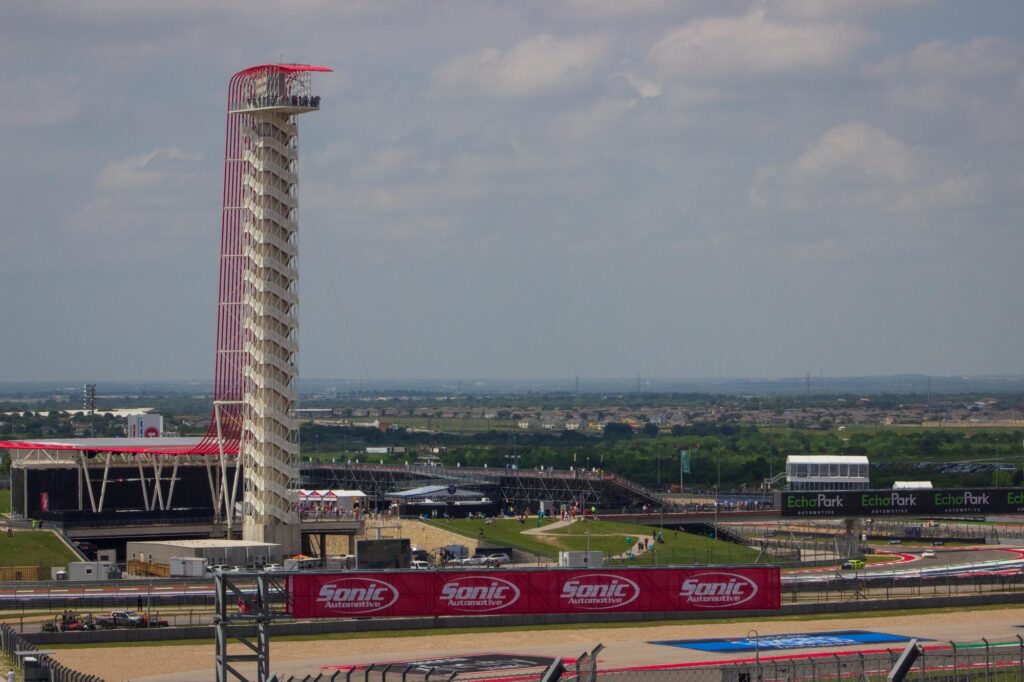 A tall red and white observation tower at a racetrack