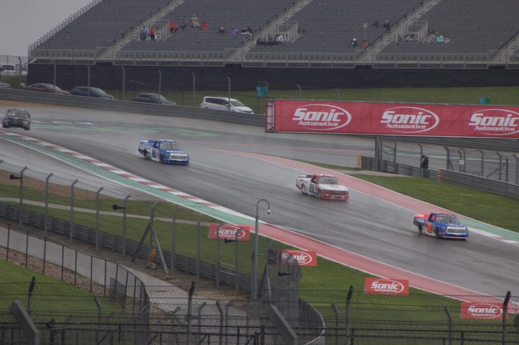 Four stock trucks racing in the rain on a racetrack
