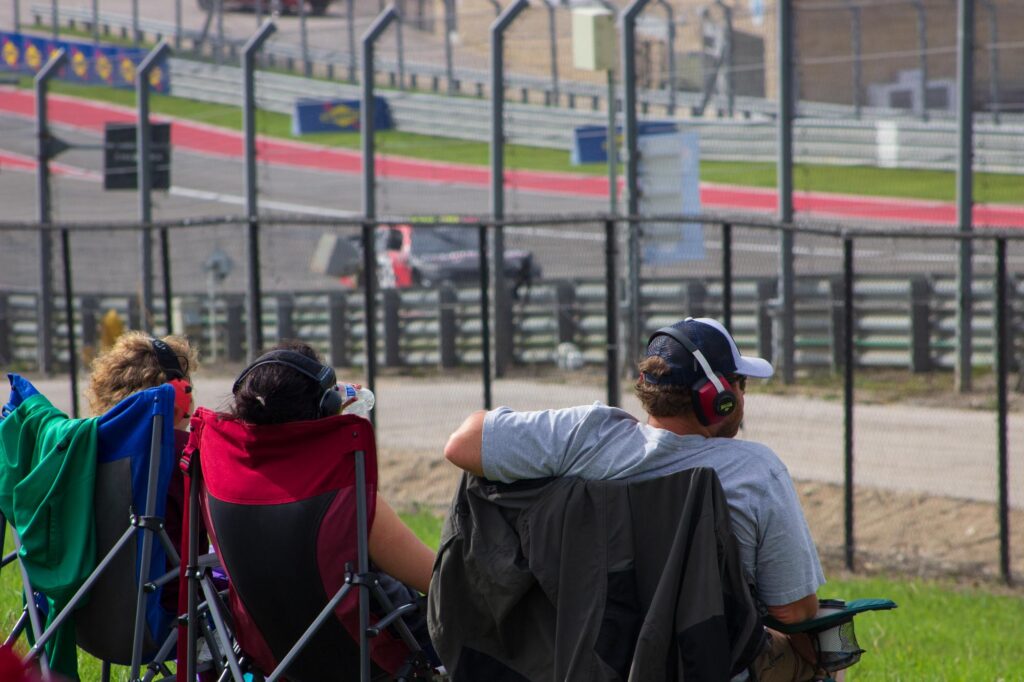 People in camping chairs watching stock cars race at a track