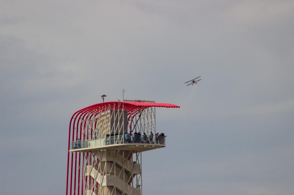A biplane flying with an observation tower in the foreground