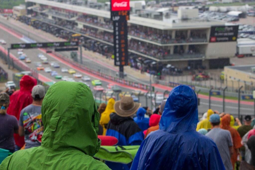 People in colorful ponchos watching stock cars race