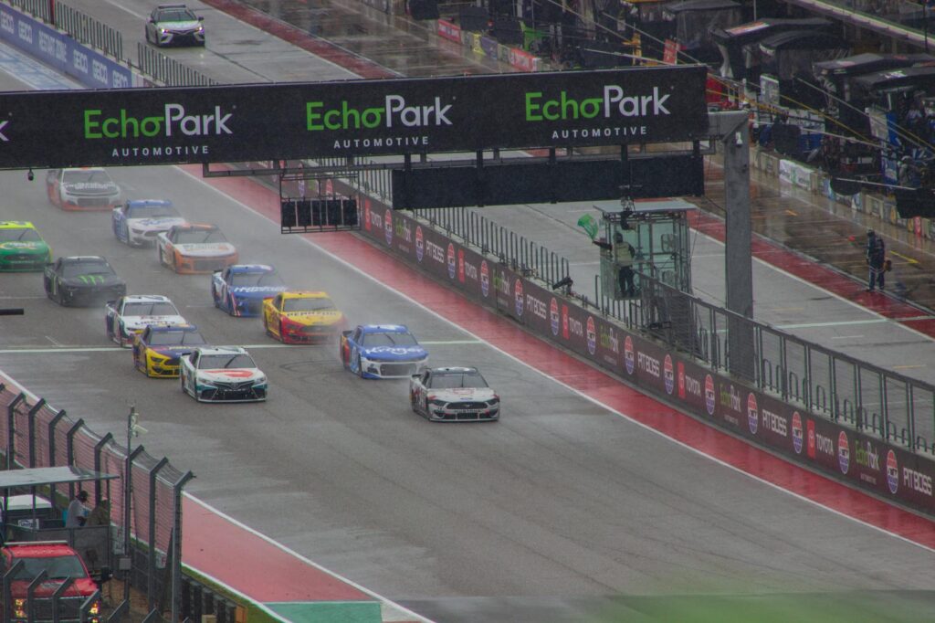 Stock cars racing on a course in the rain