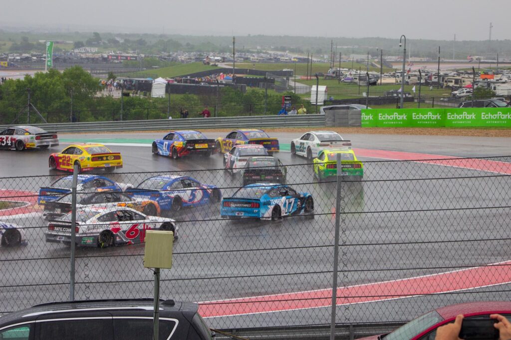 Stock cars racing on a course in the rain