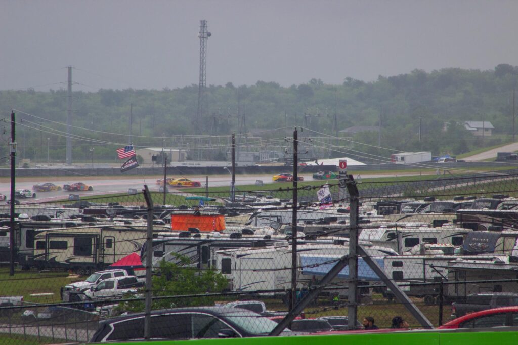 Stock cars racing in the distance on a course in the rain