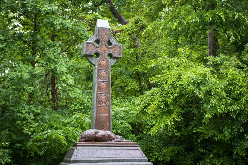 A brown memorial cross in the middle of a forest