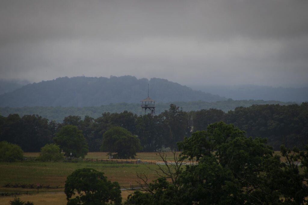 A viewing tower in the distance with a small wooded hill in the background