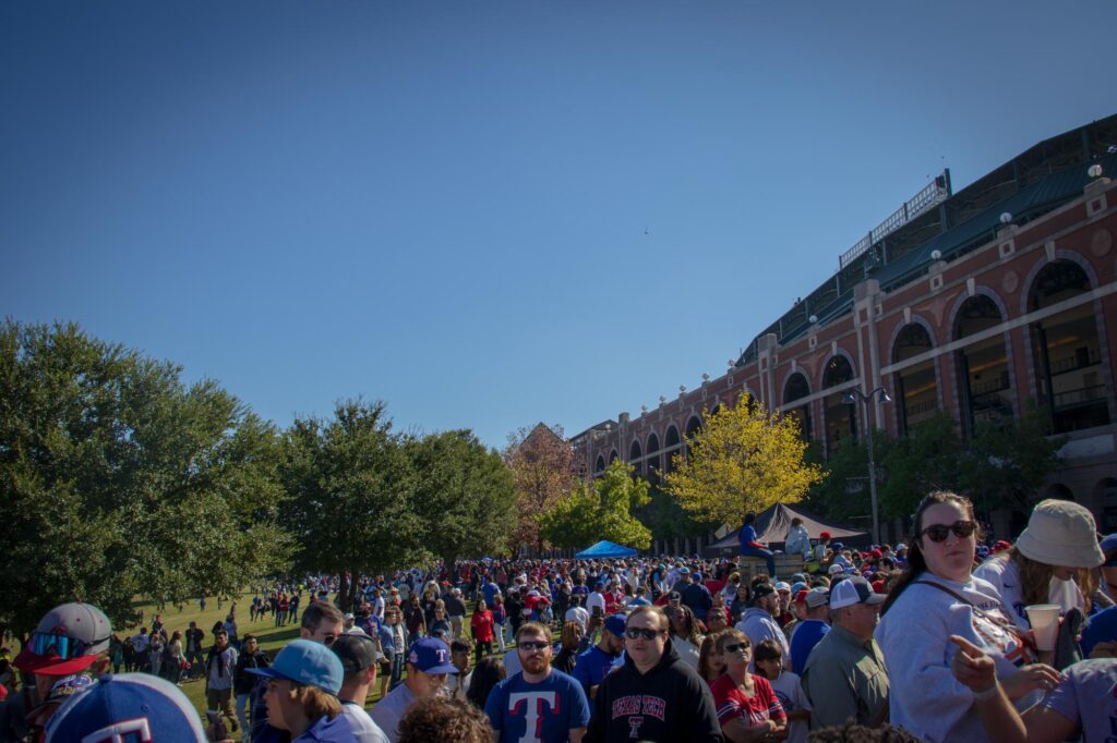 People lining up for a parade outside of a baseball stadium