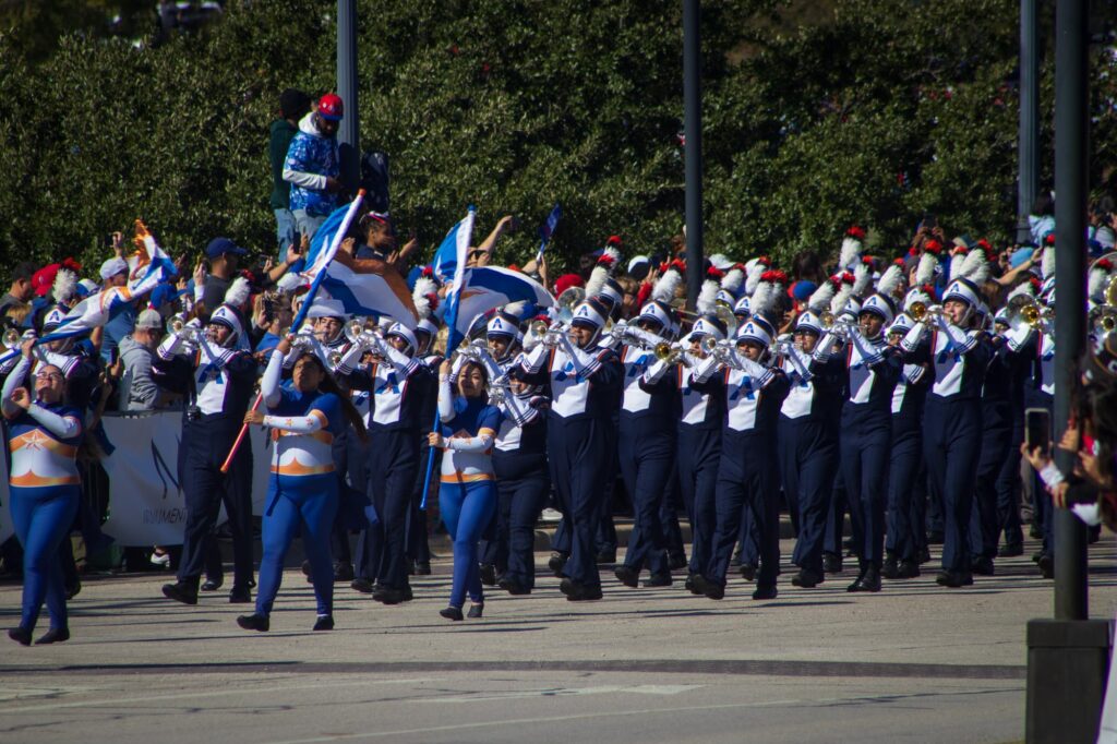 A marching band in navy blue and white uniforms marching in a parade