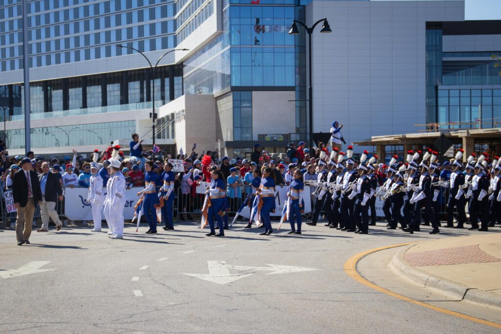 A marching band in navy blue and white uniforms marching in a parade